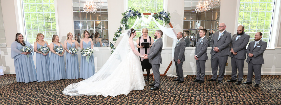 Wedding ceremony, bride and groom with their wedding party in front of large windows